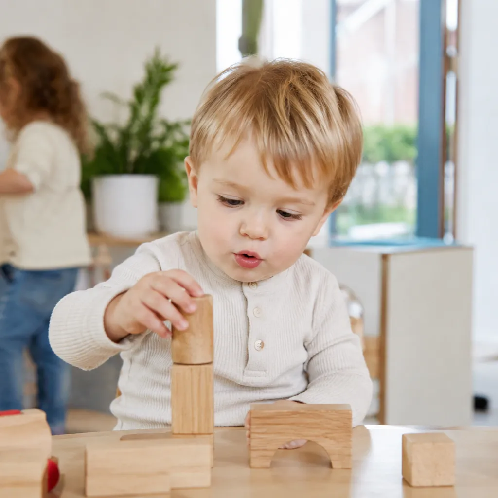 Kind speelt op kinderdagverblijf met houten blokken